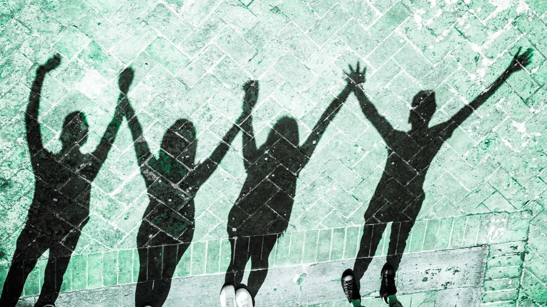 Shadows of four people holding hands and raised in the air